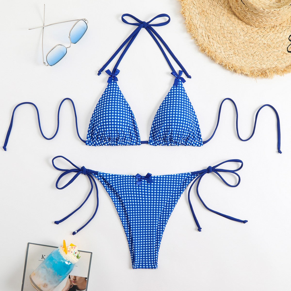 Blue gingham bikini set with sunglasses and a hat on a white background