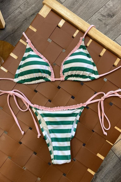 Green and white striped bikini with pink accents on a table