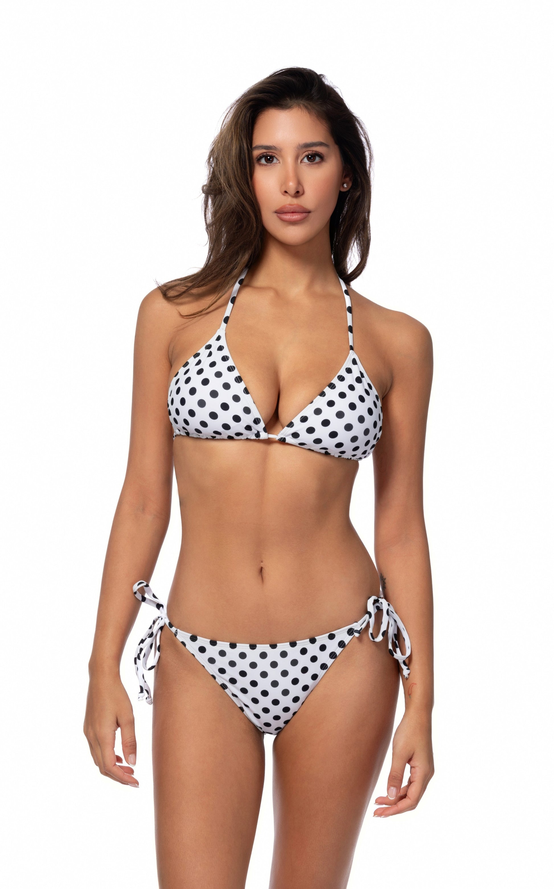 Front view of a woman wearing a black and white polka dot bikini on a white background